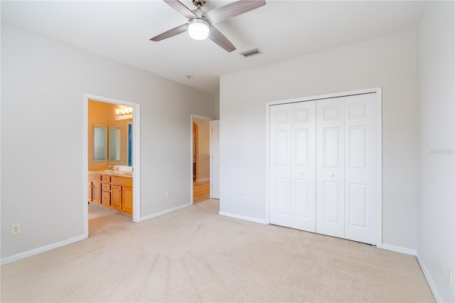 unfurnished bedroom featuring a closet, light colored carpet, visible vents, ensuite bath, and baseboards