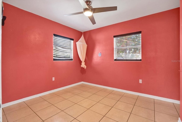 empty room featuring a ceiling fan, light tile patterned flooring, and baseboards