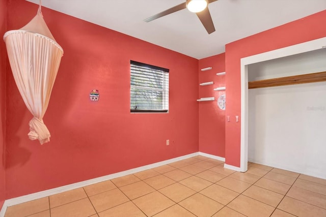 unfurnished bedroom with a ceiling fan, a closet, light tile patterned flooring, and baseboards