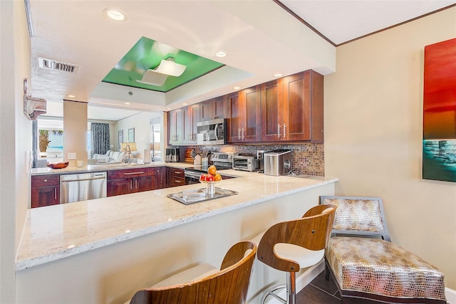 kitchen with tasteful backsplash, visible vents, light stone counters, a peninsula, and stainless steel appliances