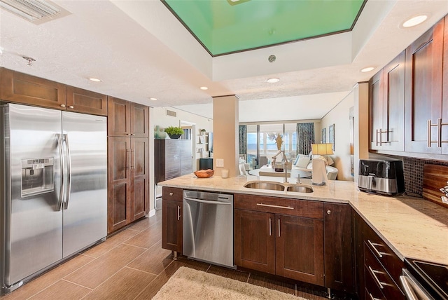 kitchen with stainless steel appliances, a sink, visible vents, and light stone countertops