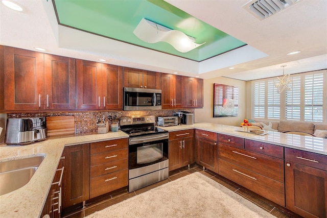 kitchen featuring light stone counters, a peninsula, visible vents, appliances with stainless steel finishes, and tasteful backsplash