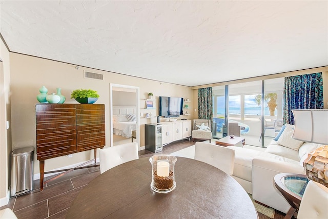 living area with a wall of windows, visible vents, and baseboards