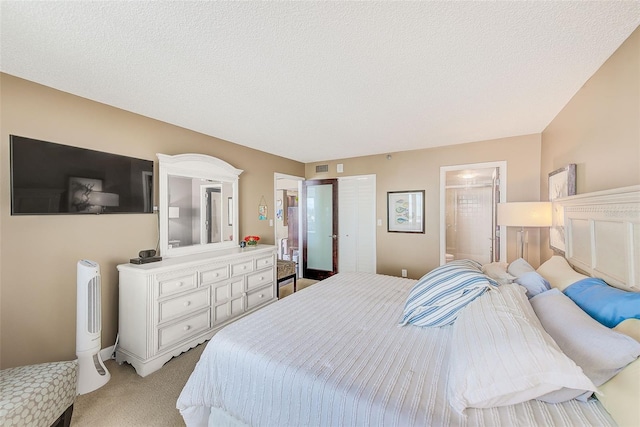 bedroom with ensuite bath, a textured ceiling, and light colored carpet