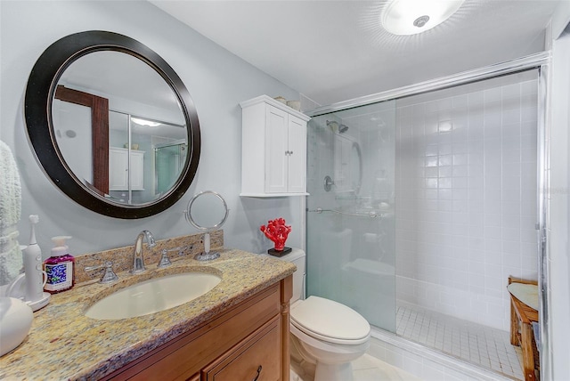 bathroom with vanity, a shower stall, and toilet