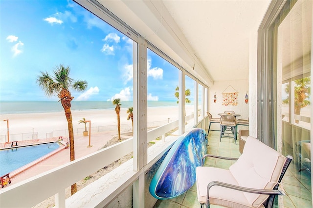 sunroom featuring a water view and a beach view