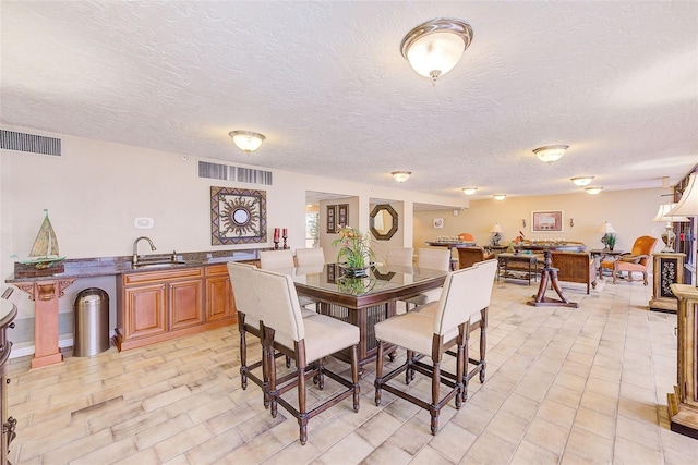 dining space featuring visible vents and a textured ceiling