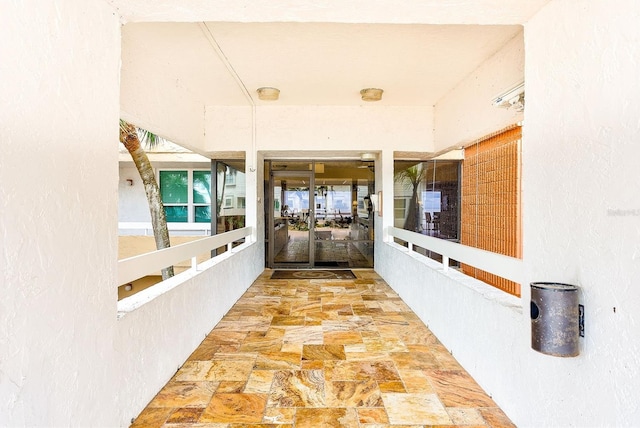 hall featuring a textured wall and stone finish flooring