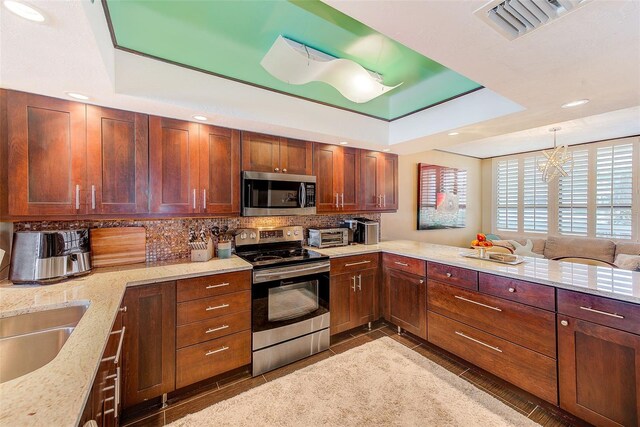 17940 Gulf Blvd Unit 2B, Redington Shores, FL 33708 - kitchen featuring stainless steel appliances, a tray ceiling, backsplash, light stone counters, and recessed lighting