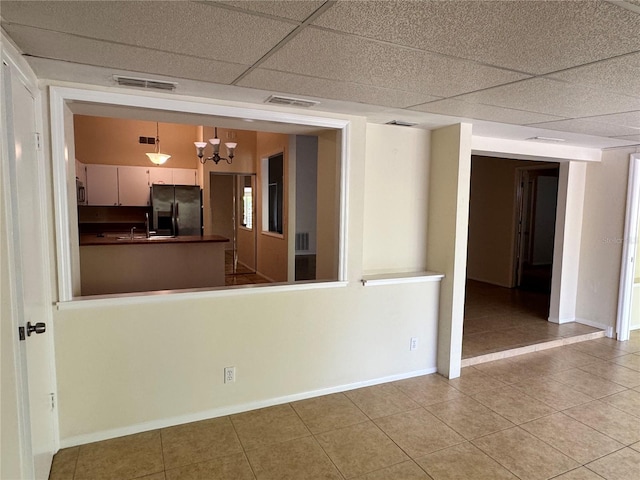 spare room with a paneled ceiling, visible vents, baseboards, and light tile patterned floors