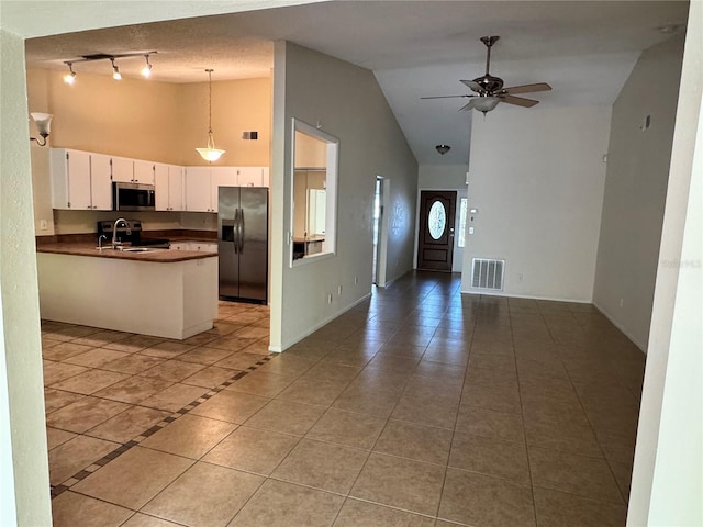 kitchen with stainless steel appliances, dark countertops, visible vents, open floor plan, and a peninsula