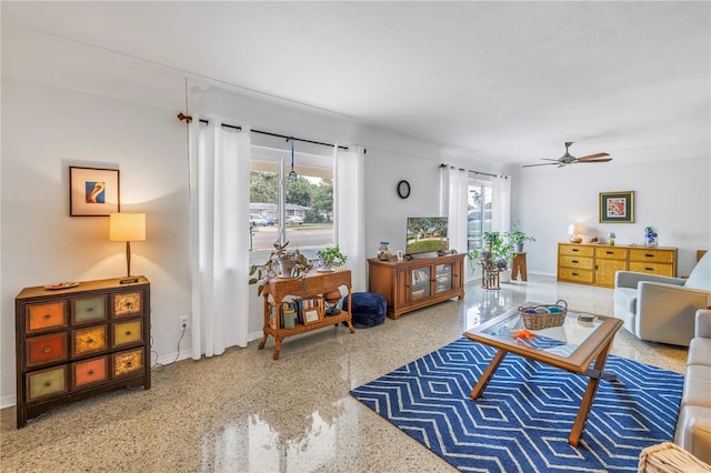 living room featuring baseboards, speckled floor, and ceiling fan