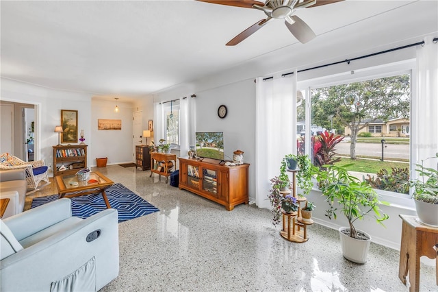 living area with baseboards, speckled floor, and ceiling fan