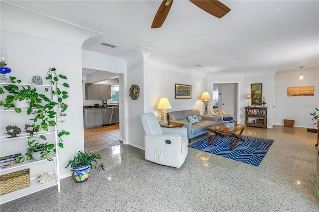 living area with visible vents, baseboards, speckled floor, and a ceiling fan