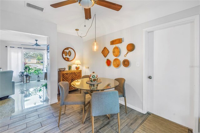 dining space featuring baseboards, a ceiling fan, visible vents, and wood tiled floor