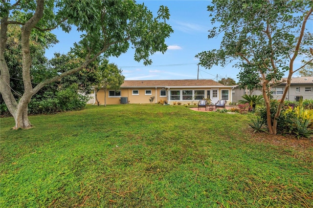 back of property with a patio, central AC unit, a lawn, and stucco siding