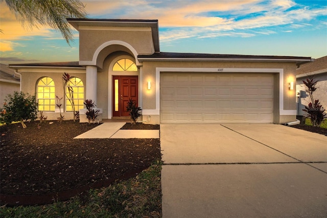 view of front of home with a garage, driveway, and stucco siding