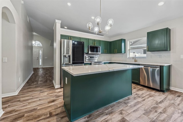 kitchen with light wood-type flooring, appliances with stainless steel finishes, backsplash, and green cabinetry