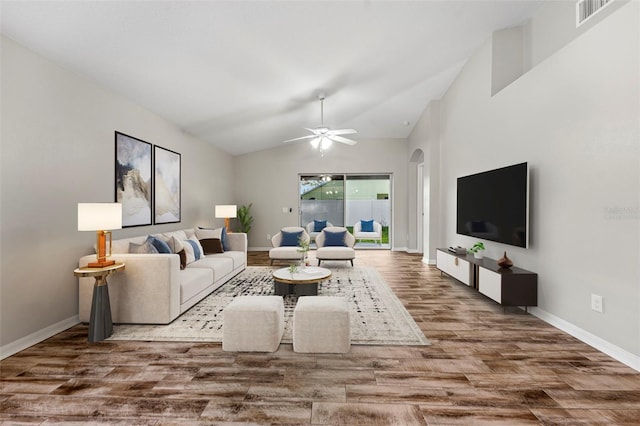 living room featuring arched walkways, visible vents, vaulted ceiling, wood finished floors, and baseboards