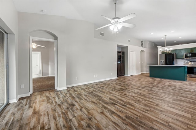 unfurnished living room with visible vents, arched walkways, wood finished floors, and ceiling fan with notable chandelier