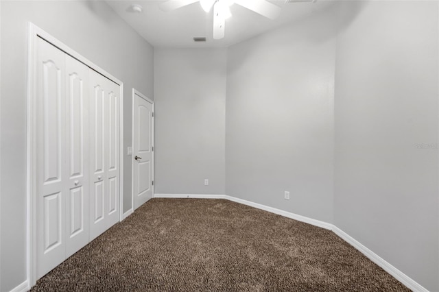 unfurnished bedroom with visible vents, baseboards, ceiling fan, dark colored carpet, and a closet