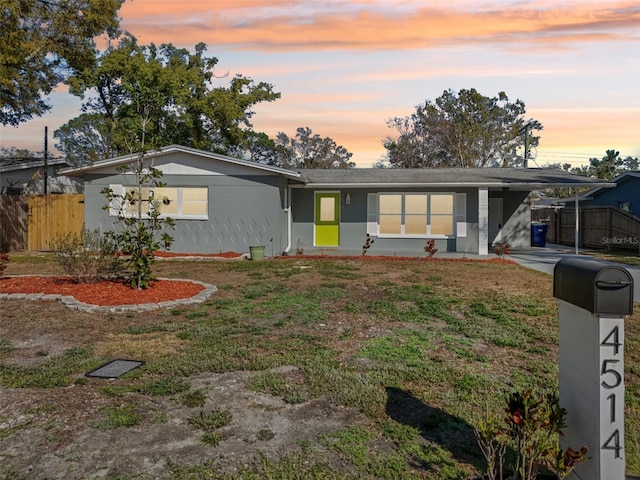 view of front of property with a yard, driveway, an attached carport, and fence