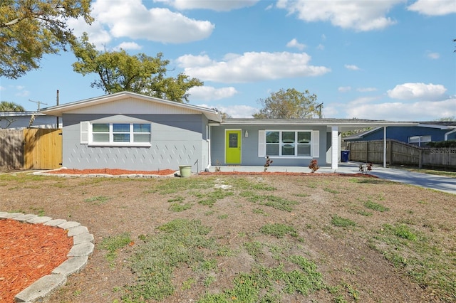 ranch-style house with driveway, fence, and a carport