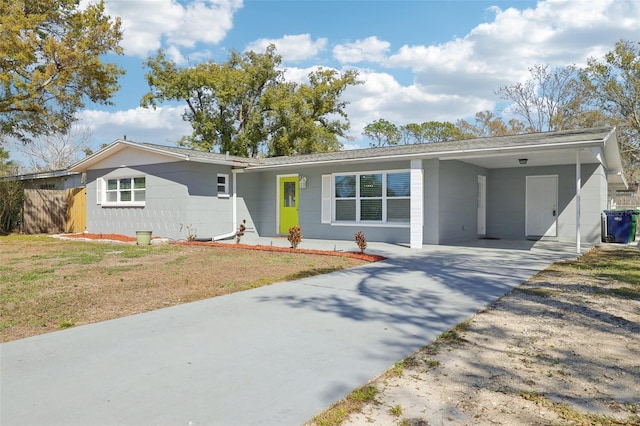 ranch-style home featuring driveway, fence, a carport, and a front yard