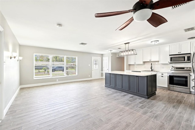 kitchen featuring light countertops, visible vents, appliances with stainless steel finishes, white cabinetry, and a sink