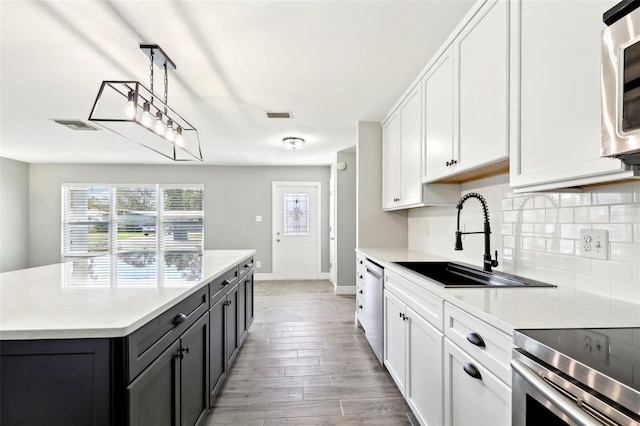 kitchen with stainless steel dishwasher, backsplash, a sink, and visible vents