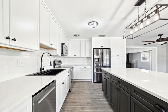 kitchen featuring stainless steel appliances, white cabinetry, a sink, and decorative backsplash