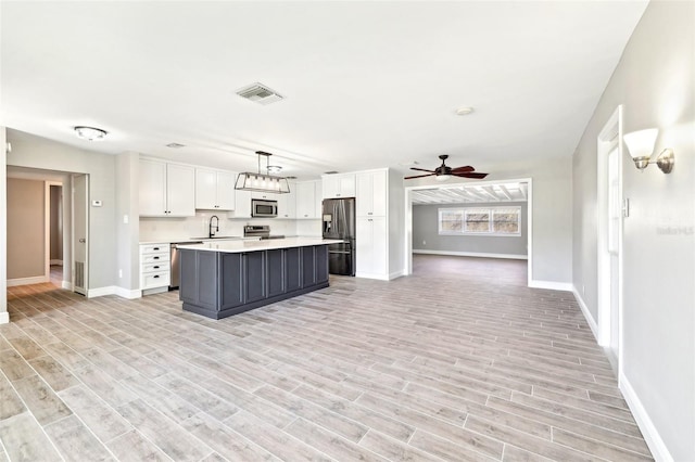 kitchen with visible vents, stainless steel appliances, light countertops, white cabinetry, and a sink