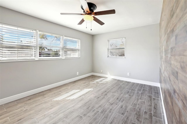 spare room featuring a ceiling fan, baseboards, and wood finished floors