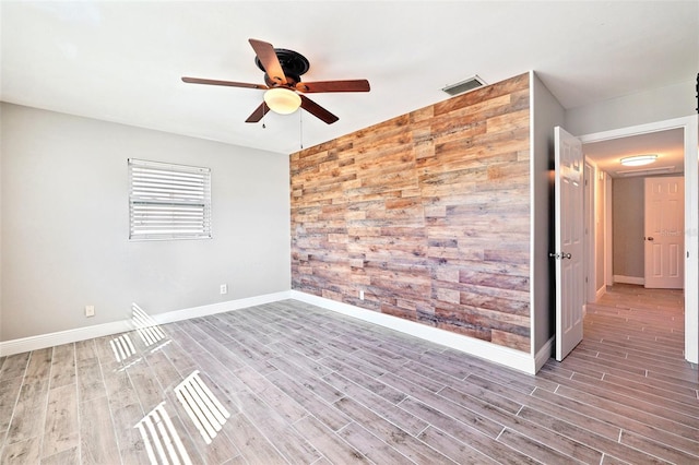 spare room featuring wood finished floors, a ceiling fan, and baseboards