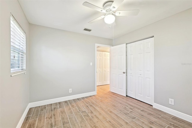 unfurnished bedroom featuring baseboards, visible vents, a ceiling fan, light wood-style floors, and a closet