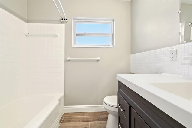 bathroom with baseboards, toilet, wood tiled floor, bathtub / shower combination, and vanity