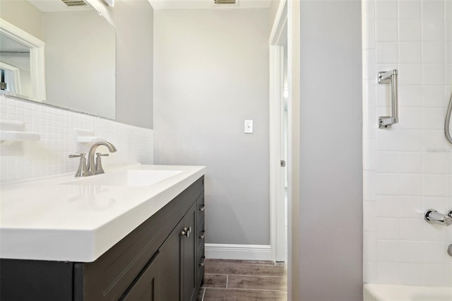 full bathroom featuring vanity, baseboards, backsplash, and wood finish floors