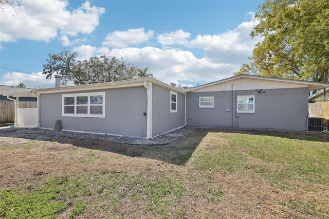 rear view of property with a yard, cooling unit, and fence