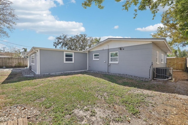 rear view of house featuring a yard, fence, and central AC unit