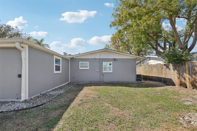 back of property with a yard, central AC unit, and fence