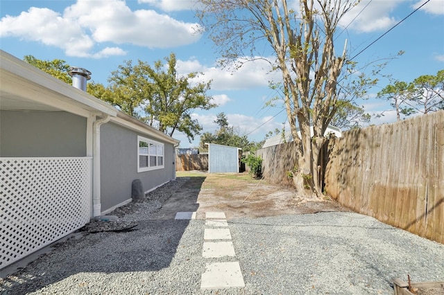 view of yard featuring a storage shed, an outdoor structure, and fence