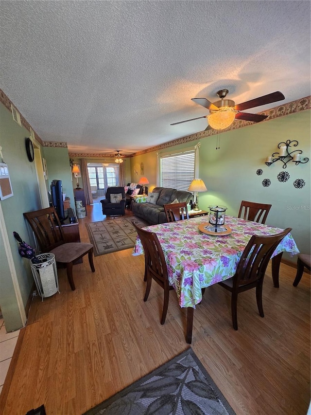 dining area with ceiling fan, a textured ceiling, and wood finished floors