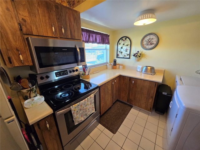 kitchen featuring washer / dryer, light tile patterned floors, appliances with stainless steel finishes, and light countertops