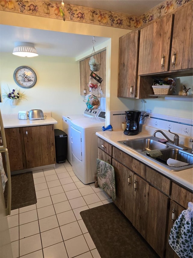 kitchen with light tile patterned floors, washing machine and dryer, light countertops, and a sink