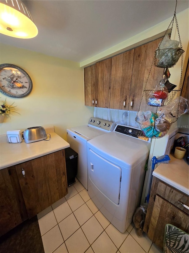 clothes washing area with cabinet space, washing machine and dryer, and light tile patterned floors