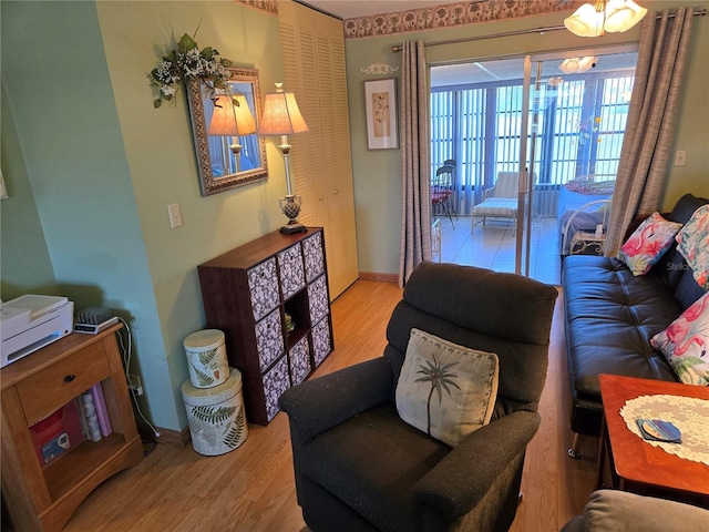 living area with an inviting chandelier, baseboards, and wood finished floors