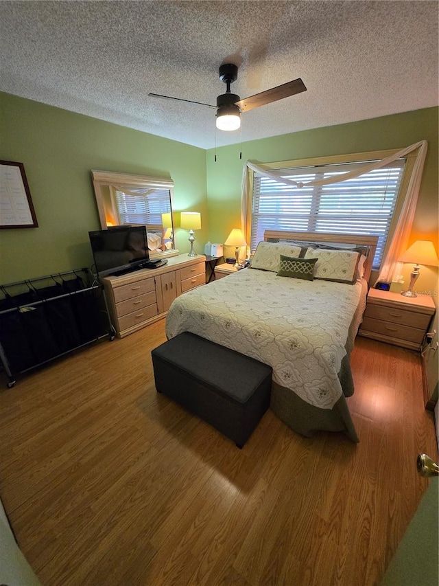 bedroom with a ceiling fan, a textured ceiling, and light wood finished floors