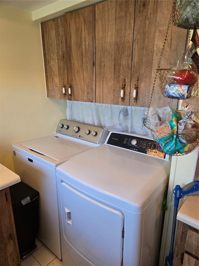 laundry area with cabinet space, washing machine and dryer, and light tile patterned floors