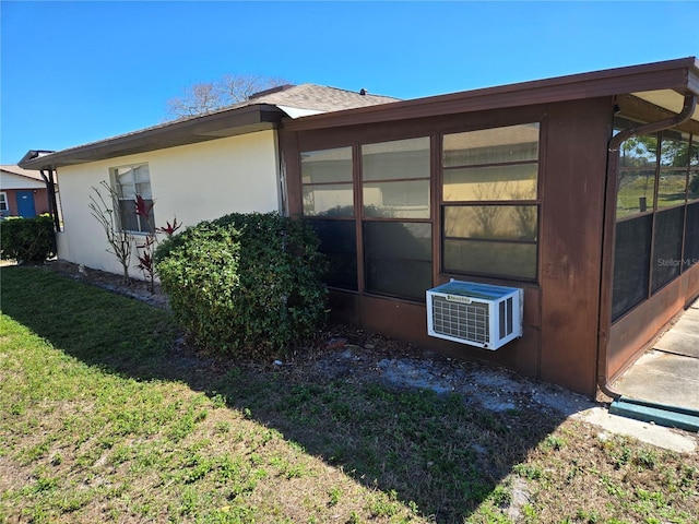 view of home's exterior featuring a sunroom, cooling unit, a lawn, and stucco siding