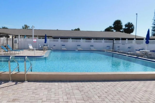 pool with a patio area and fence